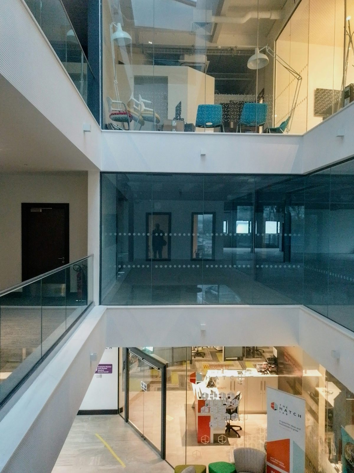 Atrium de bureaux contemporain sur plusieurs niveaux, avec passerelles et cloisons vitrées.